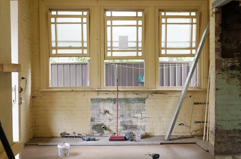 An empty room featuring large windows, ready for renovation in Sydney, Australia.