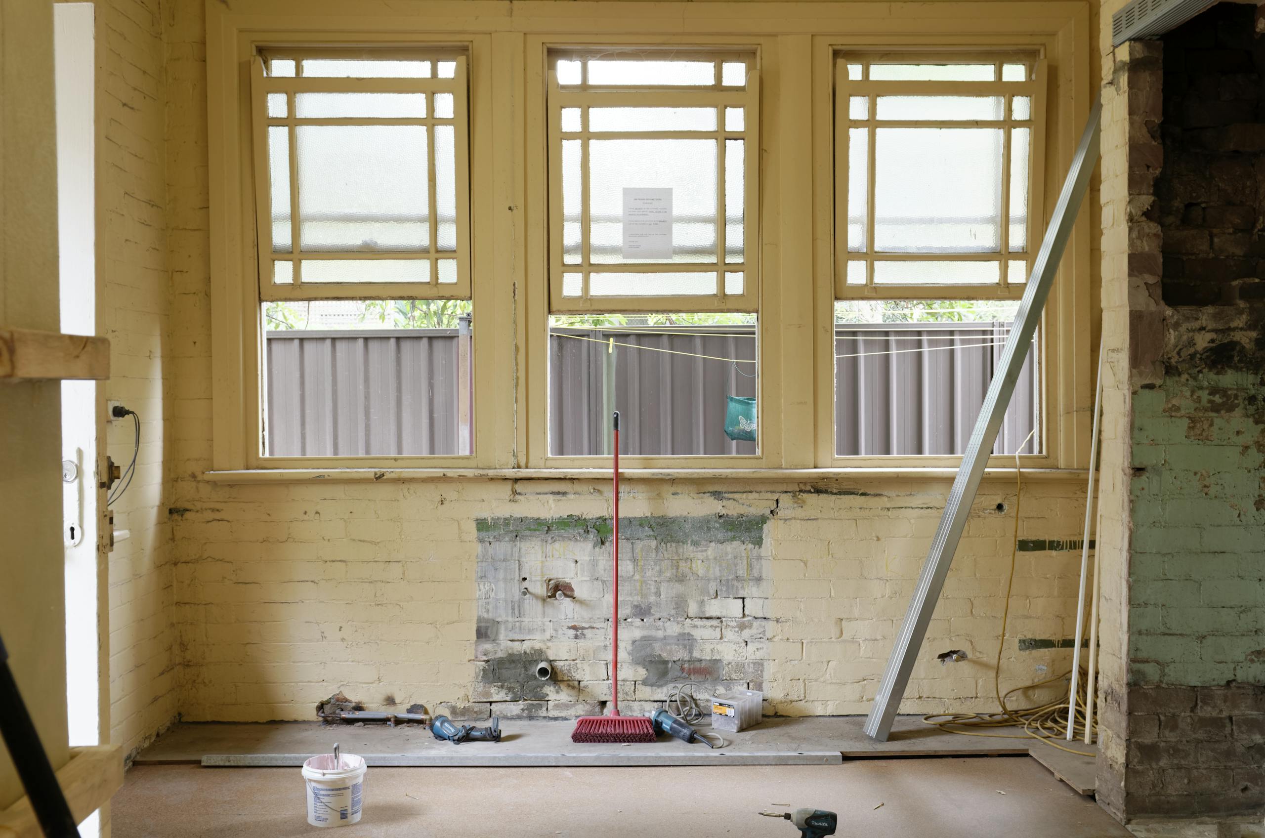 An empty room featuring large windows, ready for renovation in Sydney, Australia.