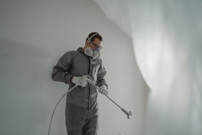 Person in protective gear painting a wall, showcasing house renovation work.