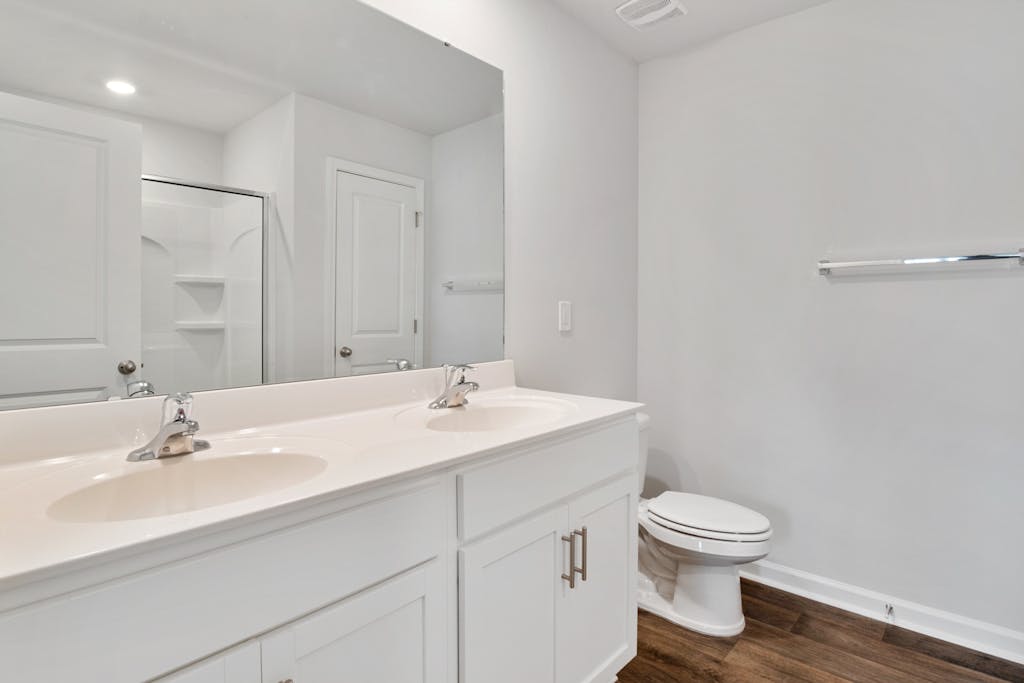 Bright modern bathroom interior featuring double sinks, mirror, and shower.