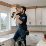 Skilled carpenter in uniform installing custom crown molding in modern Vancouver kitchen renovation with precision tools and authentic details.